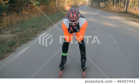 Training an athlete on the roller skaters. Biathlon ride on the roller skis with ski poles, in the Training an athlete on the roller skaters. Biathlon ride on the roller skis with ski poles, in the 46487441