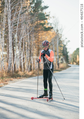 Training an athlete on the roller skaters. Biathlon ride on the roller skis with ski poles, in the Training an athlete on the roller skaters. Biathlon ride on the roller skis with ski poles, in the 46487518