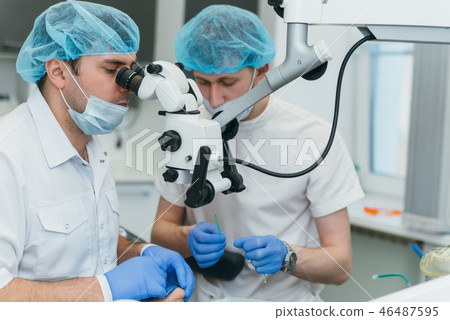 Doctor used microscope. Dentist is treating patient in modern dental office. Operation is carried 46487595