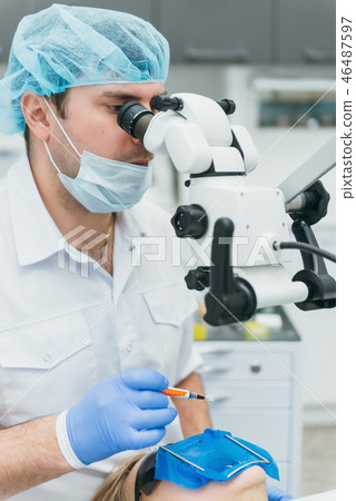 Doctor used microscope. Dentist is treating patient in modern dental office. Operation is carried 46487597