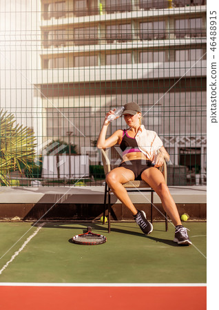 Woman tennis player drinking water from bottle Woman tennis player drinking water from bottle 46488915