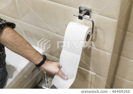 Close-up roll toilet paper in restroom with hand pulling. 46489168