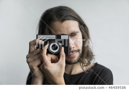 Handsome young bearded man with a long hair and in a black shirt holding vintage old-fashioned film Handsome young bearded man with a long hair and in a black shirt holding vintage old-fashioned film 46489586