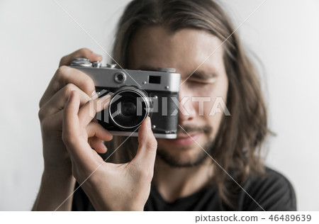 Handsome young bearded man with a long hair and in a black shirt holding vintage old-fashioned film 46489639