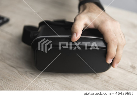VR virtual reality glasses on a table with a man hand. 46489695