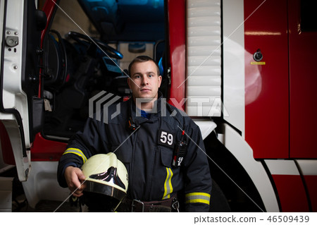 Photo of man firefighter with helmet in hand against background of fire truck Photo of man firefighter with helmet in hand against background of fire truck 46509439