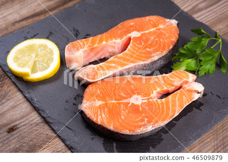 Two fresh raw salmon steaks with lemon and parsley on the rustic table 46509879