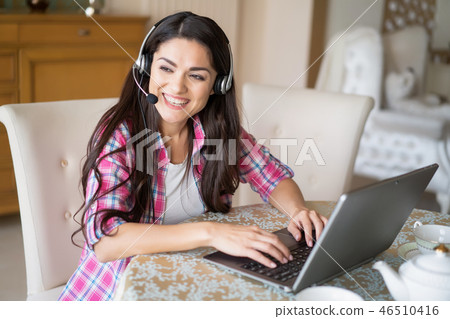 Beautiful woman works at her laptop wearing headsets Beautiful woman works at her laptop wearing headsets 46510416