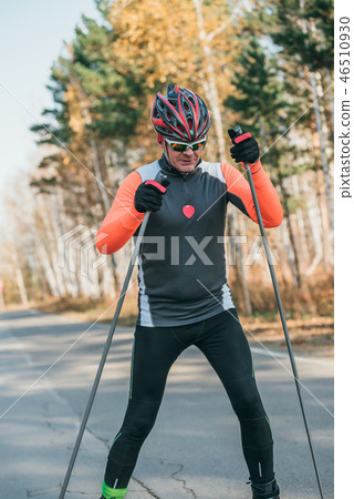 Training an athlete on the roller skaters. Biathlon ride on the roller skis with ski poles, in the 46510930