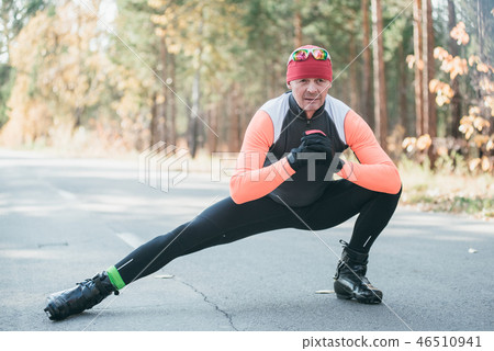Training an athlete on the roller skaters. Biathlon ride on the roller skis with ski poles, in the 46510941