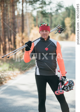 Training an athlete on the roller skaters. Biathlon ride on the roller skis with ski poles, in the Training an athlete on the roller skaters. Biathlon ride on the roller skis with ski poles, in the 46510945