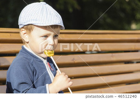 The boy is eating a delicious lollipop. The boy is eating a delicious lollipop. 46512240