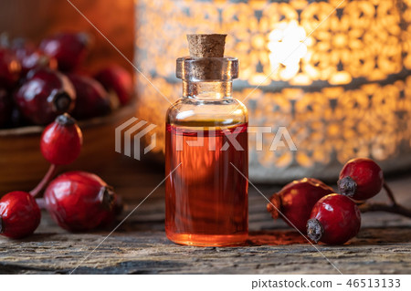 A bottle of rose hip seed oil with dried rose hips 46513133