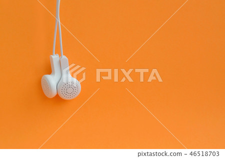 White modern headphones hanging on a bright orange background White modern headphones hanging on a bright orange background 46518703