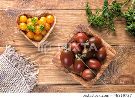 Dark red and yellow tomatoes in wooden bowls Dark red and yellow tomatoes in wooden bowls 46519727