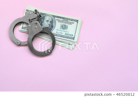 Handcuffs and us dollars lie on a pink background 46520812