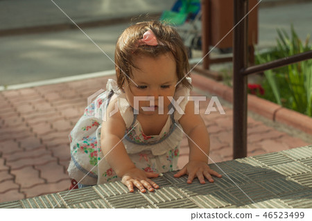 Baby girl crawling up the stairs. High angle view Baby girl crawling up the stairs. High angle view 46523499