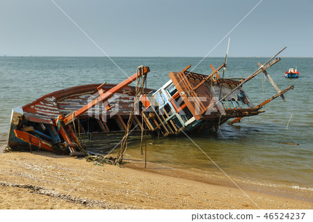 fishing boat crashed lies on its side near the shore fishing boat crashed lies on its side near the shore 46524237