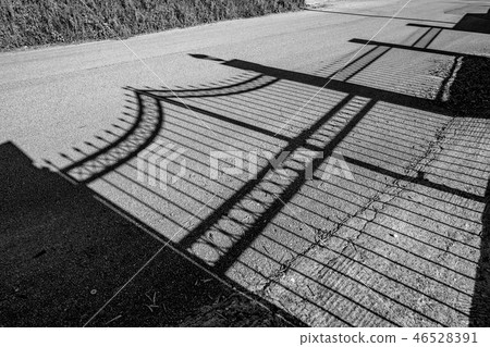 Shadow of garden fence on dirty road 46528391