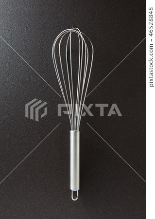 Kitchen metal beater on a black concrete background with copy space. Kitchen appliance for cooking Kitchen metal beater on a black concrete background with copy space. Kitchen appliance for cooking 46528848