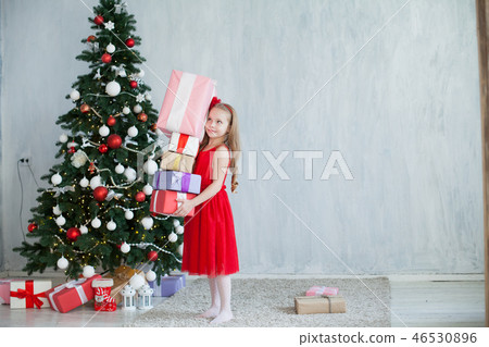 little girl opens Christmas presents new year tree 46530896