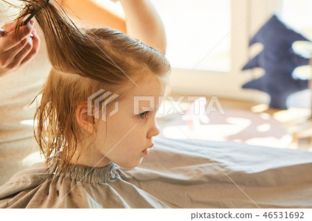 Hairdresser making a hair style to cute little girl. 46531692