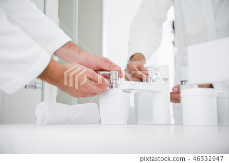 Close up of hands pushing container with liquid soap 46532947