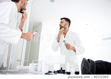 Calm man touching his beard in front of the bathroom Calm man touching his beard in front of the bathroom 46532969