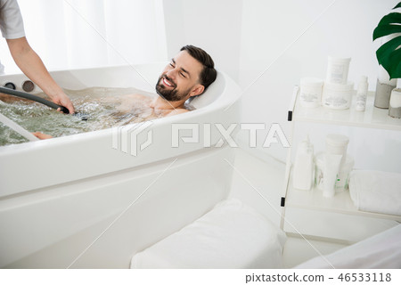 Pleased man smiling and enjoying water jets procedure Pleased man smiling and enjoying water jets procedure 46533118