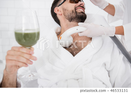 Man with green cocktail undergoing laser hair removal procedure 46533131