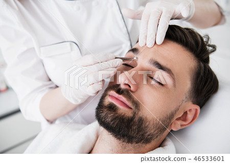 Pair of tweezers in hands of cosmetologist plucking eyebrows 46533601