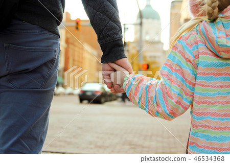 father holding the daughter hand behind traffic  46534368
