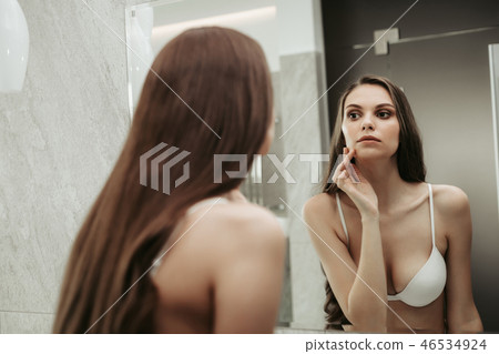 Focused lady watching at mirror in apartment Focused lady watching at mirror in apartment 46534924