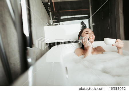 Young woman talking by phone while taking bath Young woman talking by phone while taking bath 46535052