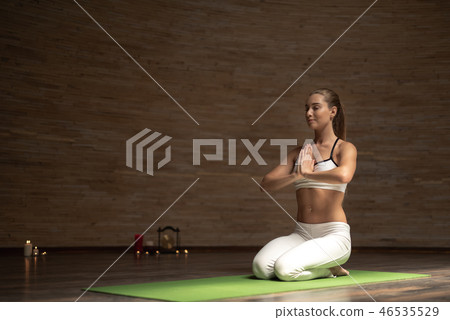 Peaceful lady sitting on her knees and smiling while meditating Peaceful lady sitting on her knees and smiling while meditating 46535529