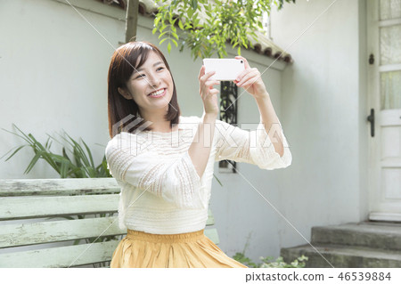 A woman taking a picture with a smartphone 46539884