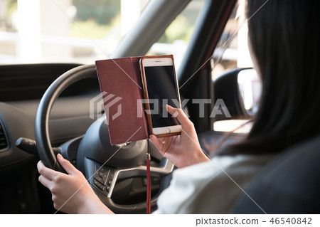 Young Japanese woman driving while looking at a smartphone 46540842