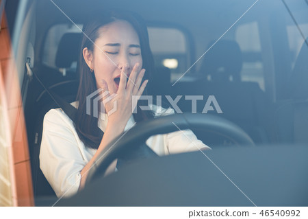 Young Japanese woman yawning while driving 46540992