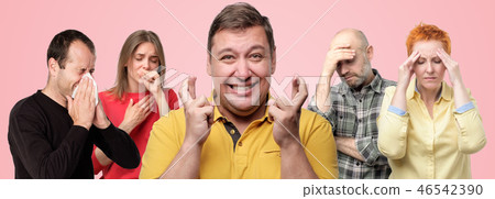 several people being ill. Mature man in the middle crossing fingers. He is afraid to catch flu. 46542390