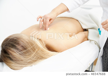 Macro detail of female hand using an insertion tube to insert a Goshin acupuncture needle in the Macro detail of female hand using an insertion tube to insert a Goshin acupuncture needle in the 46547688