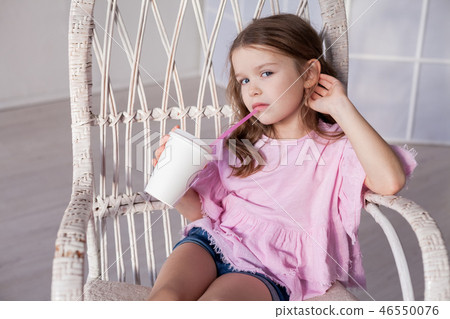 girl in pink dress drinking milkshake in a Chair 46550076