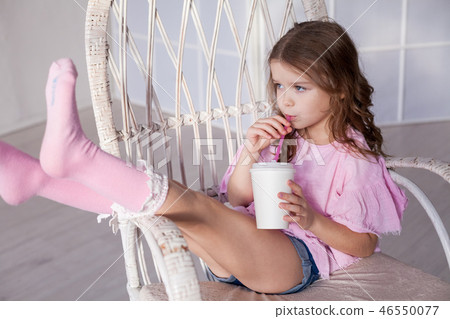 girl in pink dress drinking milkshake in a Chair girl in pink dress drinking milkshake in a Chair 46550077