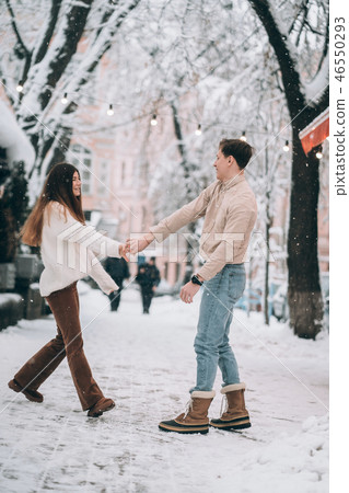 young guy and beautiful girl have fun on a snowy street. Couple in sweaters. 46550293