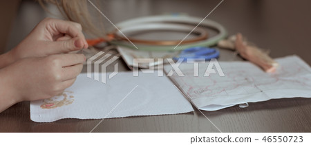 Children's hands embroider on a dark background. 46550723