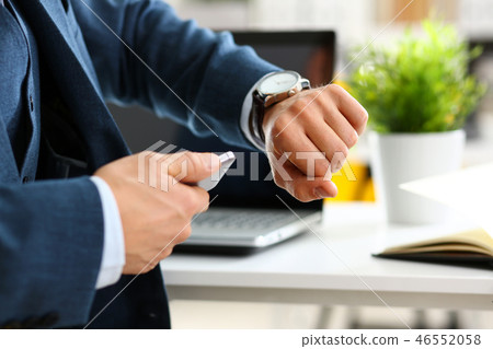 Man in suit and tie check out time at silver wristwatch 46552058