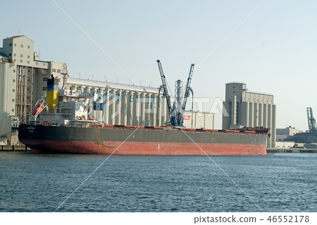 A ship handling cargo with a silo wharf 46552178