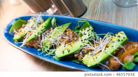 Delicious salmon tartare garnish with avocado on blue plate Delicious salmon tartare garnish with avocado on blue plate 46557038
