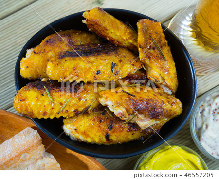 Fried chicken wings served in black bowl, two sauses and bread 46557205