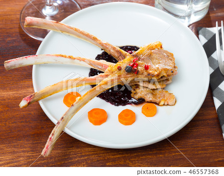 Baked lamb ribs with spicy sauce and carrots served at plate 46557368