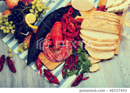 Smoked sturgeon, lobster, crayfishes, bread, cheese and fruits on wooden surface Smoked sturgeon, lobster, crayfishes, bread, cheese and fruits on wooden surface 46557443